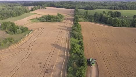 Aerial-View-Flying-Over-Combine-Harvester-In-Rural-Countryside-During-Sunset-In-Slow-Motion