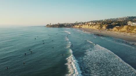 Stunning-4k-aerial-shot-of-the-coastline-of-San-Diego-in-California-with-surfers-in-the-Ocean-while-sunset-at-pacific-beach