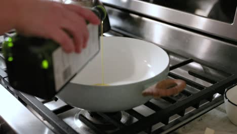Woman-Pouring-Olive-Oil-Into-Frying-Pan-In-4K