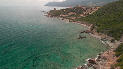 Scenic-View-Of-Tropical-Sea-Water-And-Green-Mountains-On-A-Beautiful-Sunny-Day-In-Sardinia,-Italy---aerial-drone-shot