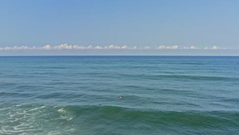 Aerial:-surfers-paddling-over-waves-and-sitting-observing-ocean