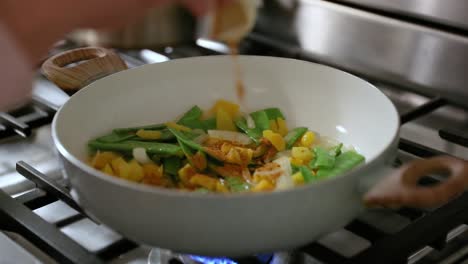 Woman-Adding-Spice-To-Frying-Pan-Of-Cooking-Vegetables-In-Slow-Motion
