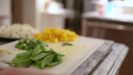Woman-Preparing-Snow-Peas-Over-Cutting-Board-In-Slow-Motion