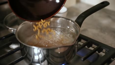 Pouring-Dry-Pasta-Into-Boiling-Pot-Of-Water-In-Slow-Motion