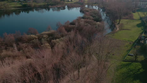 Wonderful-Calm-Lake-Surrounded-By-Trees-And-Fields-During-Sunset-In-Annone-Lake,-Northern-Italy---aerial-drone-wide-shot