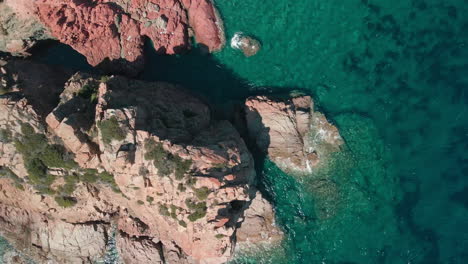 Top-Down-View-Of-Mountain-Cliff-And-Blue-Tropical-Sea-Water-During-A-Sunny-Day-Of-Summer-In-Sardinia,-Italy---aerial-static-shot