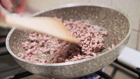 Woman-Mixes-Minced-Beef-With-Wooden-Spoon-While-Cooking-In-Pan-On-Stove---close-up,-static-shot