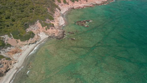 Costa-Mediterránea-Con-Playa-Y-Olas-Cristalinas-Del-Mar-Azul-Durante-El-Verano-En-Cerdeña,-Italia---Toma-Aérea-De-Drones