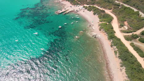 Panoramic-View-On-The-Beautiful-Mediterranean-Coast-With-Tropical-Blue-Sea-And-Moored-Boats-Under-The-Hot-Summer-Sun-In-Sardinia,-Italy---Aerial-drone-shot