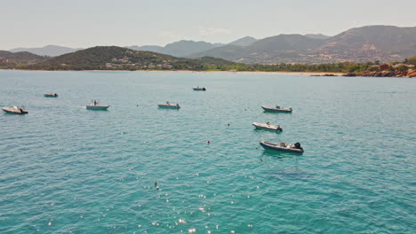 Gruppe-Von-Booten,-Die-An-Einem-Sonnigen-Tag-In-Sardinien,-Italien,-Im-Tropischen-Blauen-Wasser-Festgemacht-Sind---Luftbild,-Statische-Aufnahme