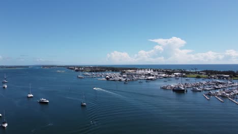 Aerial-view-of-a-port-and-a-bay-with-sailing-boats-and-a-motor-boat-passing-by