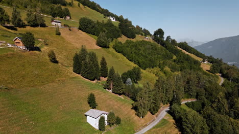 Idílico-Paisaje-Rural-Con-Casas-En-Montañas-Densamente-Verdes-A-Lo-Largo-De-La-Carretera-Asfaltada-Durante-El-Verano-Soleado-En-Los-Alpes-Orobie,-Norte-De-Italia