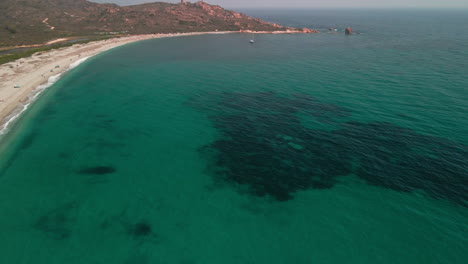 Hermosa-Playa-A-Lo-Largo-De-La-Costa-Con-Mar-Azul-Verde-Y-Montañas-Mediterráneas-En-Segundo-Plano-En-Cerdeña,-Italia---Toma-Aérea-De-Drones