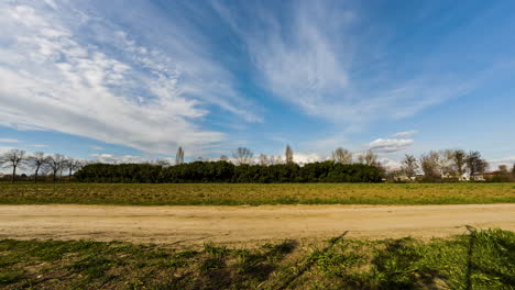 Countryside-Landscape-With-Farm-Field-And-Blue-Sky-With-Clouds-On-A-Sunny-Spring-Day---Timelapse-wide-shot