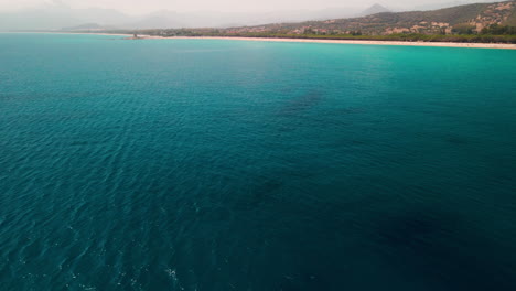 Ruhiges-Blaues-Mittelmeer-Mit-Langem-Strand-Und-Hügeln-Im-Hintergrund-An-Einem-Sonnigen-Tag-In-Sardinien,-Italien---Luftbild,-Panoramische-Aufnahme