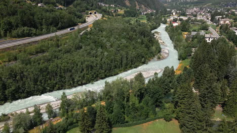 Dense-Forest-Mountain-River-Near-Highway-With-Village-Background-In-Morgex-Valle-d'Aosta,-Italy