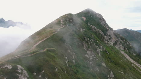 Aerial-view-of-a-trail,-up-in-the-mountains,-foggy-day,-in-Italy---rising,-drone-shot