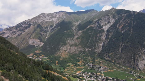 Aerial-View-of-Italian-Alps-and-Small-City-in-Picturesque-Valley-on-Sunny-Summer-Day