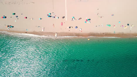 Bird's-Eye-View-From-Above-Of-The-Beach-With-Colorful-Umbrellas-And-Tourists-In-The-Beautiful-Tropical-Sea-Of-Emerald-Coast,-Sardinia,-Italy---Aerial-drone,-static-shot