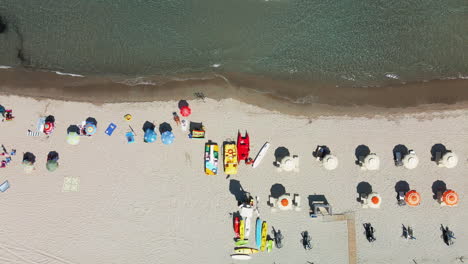 Top-Down-View-Of-White-Sand-Beach-With-Colorful-Umbrellas-And-Tourists-Enjoying-The-Summer-Vacation-In-Sardinia,-Italy---aerial-drone-shot