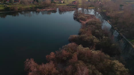 Calm-Water-Lake-Surrounded-By-The-Nature-Of-The-Italian-Countryside-During-Sunset-In-Lago-di-Annone,-Italy---aerial-drone-shot