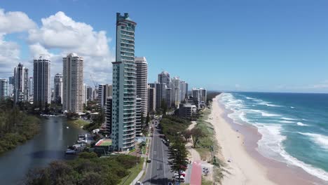 Drone-ascending-and-showing-skyscrapers,-a-beautiful-sandy-beach-and-a-river-as-well