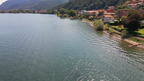 Calm-Waters-Of-Lake-Como-With-A-View-Of-The-Shore-And-Residential-Houses-With-Green-Mountains-In-Background-At-Daytime-In-Italy---aerial-drone-forward