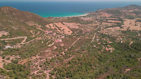 Stunning-Countryside-Landscape-With-Green-Vegetation-And-Dirt-Roads,-Beautiful-Blue-Sea-In-The-Background-In-Sardinia,-Italy---aerial-panoramic-shot