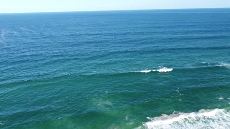 Drone-flying-out-to-sea,-waves-breaking-below