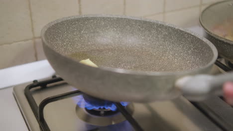 Woman-Holding-A-Non-stick-Pan-Tilting-To-Cover-Surface-With-Butter-and-Oil-Over-Medium-Fire