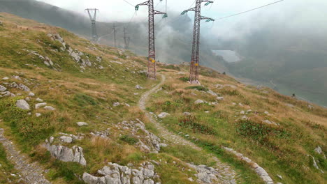Filmischer-Blick-Auf-Die-Hochspannungsmasten-über-Den-Wiesen-Des-Alpinen-Berges-In-Passo-San-Marco,-Norditalien---Luftdrohnenaufnahme
