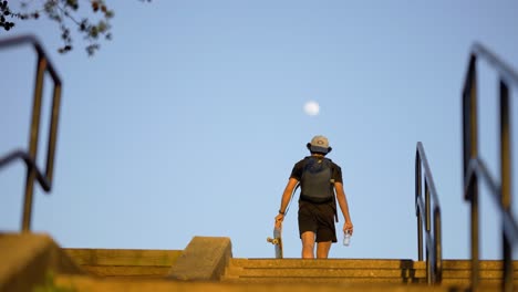 Teen-Walking-With-Skateboard-With-Moon-In-The-Sky