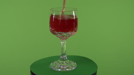 red-liquid-pouring-into-fancy-spinning-glass-in-front-of-chroma-green-screen