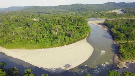 Majestic-river-surrounded-by-dense-forest-and-small-mountain-range,-aerial-drone-view