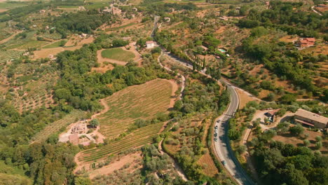 Valle-Toscano-Con-Campos-Y-Vegetación-Verde-En-Montalcino,-Italia---Toma-Aérea-De-Drones