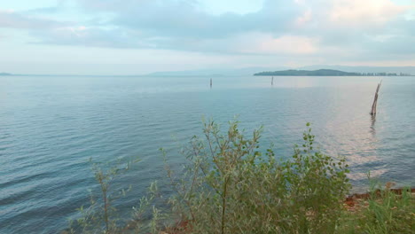 Calm-Waters-Of-The-Lake-Trasimeno-In-Tuscany,-Italy-During-Sunrise---aerial-drone-shot