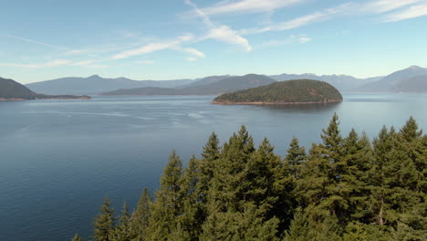 Drone-over-trees-towards-a-small-island-on-the-Pacific-coast,-BC-Canada