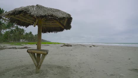 Sombrilla-De-Paja-Y-Bosque-De-Palmeras-En-Un-Día-Ventoso-En-La-Playa-De-Ecuador