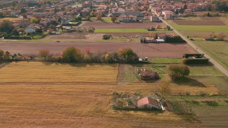 Peasant-Fields-Near-The-Inhabited-Center-With-Residential-Houses-In-The-Background-In-North-Italy---aerial-drone-shot