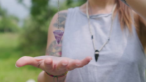 Woman-Making-Pendulum-Move-Focusing-With-Hands-Outdoors---close-up