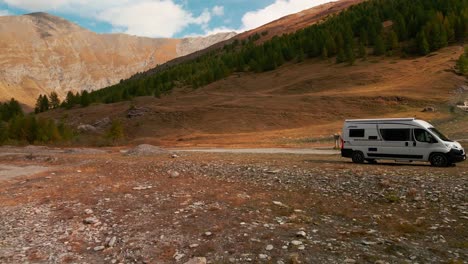 Flowing-River-With-Camper-Van-Parked-Against-Scenic-Mountainscape-During-Autumn-Season