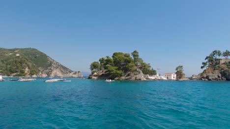 Panning-view-of-Parga-coastal-islets-with-boats-moored-on-emerald-blue-water,-touristic-destination,-Greece