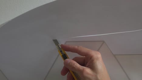 Professional-vinyl-applicator-trimming-off-excess-material-during-installation-of-design-with-sharp-scalpel-blade