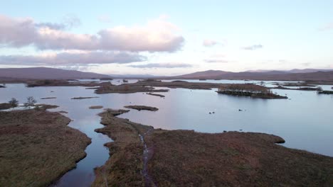 A-drone-slowly-rises-aup-and-tilts-down-towards-a-patchwork-landscape-of-islands-amongst-fresh-water-lochs-and-peat-bogs-at-sunset
