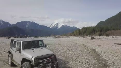 Drone-aerial-shot-of-two-jeeps-by-the-water-desert-in-No-Man's-Land-in-British-columbia