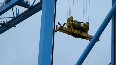 Crane-Spreader-Moving-Along-Gantry-Crane-On-Overcast-Day-At-APM-Maasvlakte-Terminal-In-Rotterdam