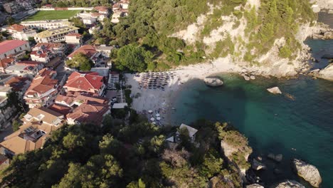 Orbiting-view-of-Golfo-Beach-in-Parga-Village,-small-turquoise-beach-water-surrounded-by-rocks,-Greece