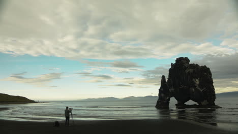 Person-taking-photographs-with-tripod-on-beautiful-coast-of-Iceland