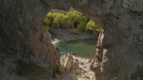 Wunderschöner-Drohnenschuss,-Der-Durch-Eine-Felsformation-In-Richtung-Eines-Wunderschönen-Flusses-In-Argentinien-Fliegt