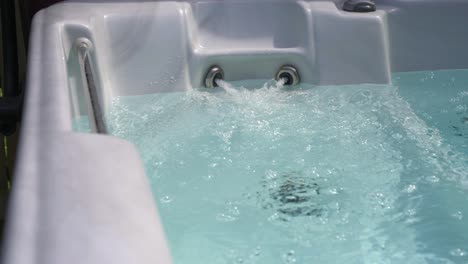 Close-up-on-private-luxury-hot-tub-of-jets-blowing-bubbles-on-sunny-summer-day